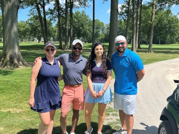 4 golfers standing in front of trees